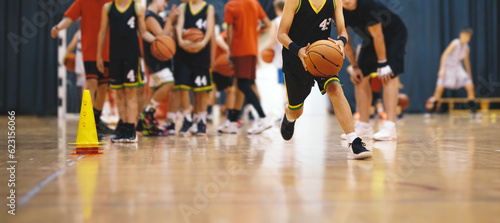 Fototapeta Naklejka Na Ścianę i Meble -  Youth Basketball Players in a Team on Training Drill. Young Boys Practice Basketball With Young Coach. Basketball Training Unit For Youth Players