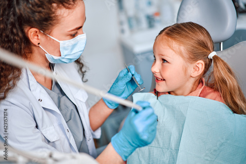 Children s dentistry. A child is sitting in a dental chair and talking to a nurse.