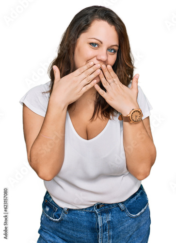 Young plus size woman wearing casual white t shirt laughing and embarrassed giggle covering mouth with hands, gossip and scandal concept