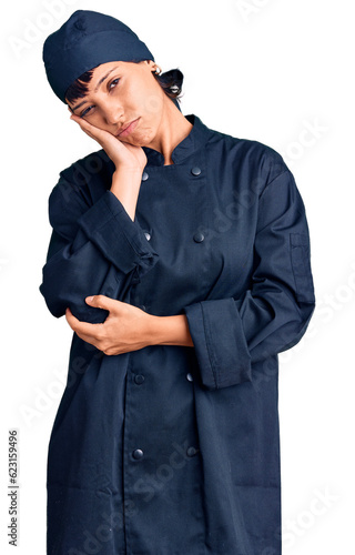 Young brunette woman with short hair wearing professional cook uniform thinking looking tired and bored with depression problems with crossed arms.