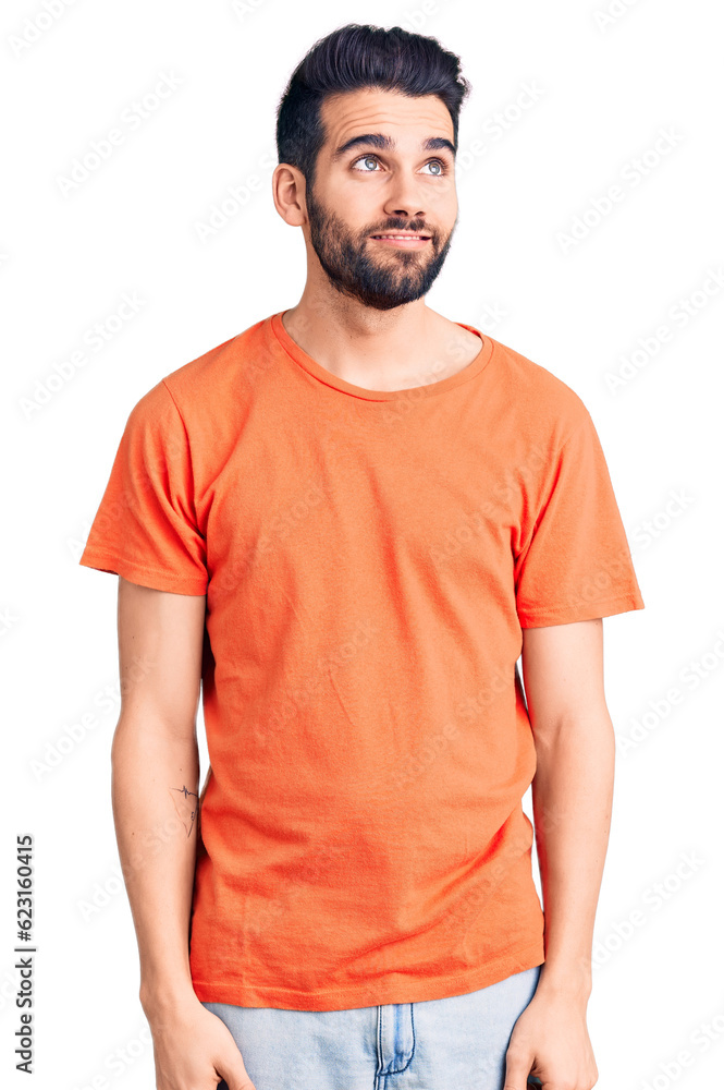 Fototapeta premium Young handsome man with beard wearing casual t-shirt smiling looking to the side and staring away thinking.