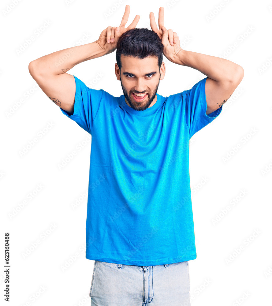 Young handsome man with beard wearing casual t-shirt posing funny and crazy with fingers on head as bunny ears, smiling cheerful Young handsome man with beard wearing casual t-shirt posing funny and crazy with fingers on head as bunny ears, smiling cheerful