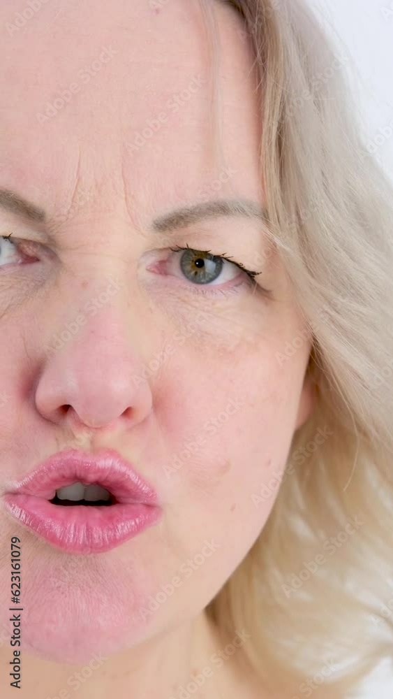 Mouth Insulting, Slow Motion the girl builds dissatisfied grimaces with her mouth lips teeth moves in different directions creating anger aggression madness close-up face of a blonde woman Mouth Insulting, Slow Motion the girl builds dissatisfied grimaces with her mouth lips teeth moves in different directions creating anger aggression madness close-up face of a blonde woman