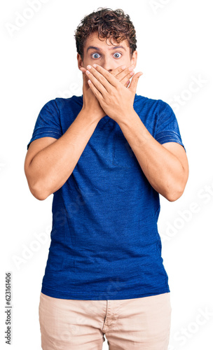 Young handsome man with curly hair wearing casual clothes shocked covering mouth with hands for mistake. secret concept.