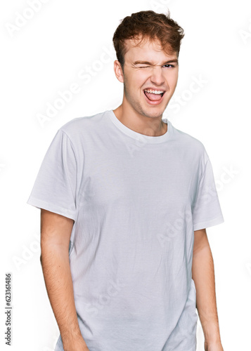 Young caucasian man wearing casual white t shirt winking looking at the camera with sexy expression, cheerful and happy face. © Krakenimages.com