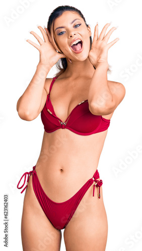 Young beautiful woman wearing bikini smiling cheerful playing peek a boo with hands showing face. surprised and exited © Krakenimages.com