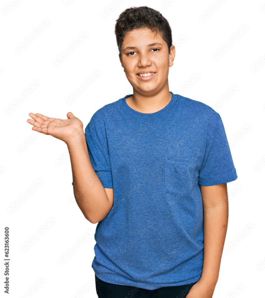 Teenager hispanic boy wearing casual clothes smiling cheerful presenting and pointing with palm of hand looking at the camera. Teenager hispanic boy wearing casual clothes smiling cheerful presenting and pointing with palm of hand looking at the camera.