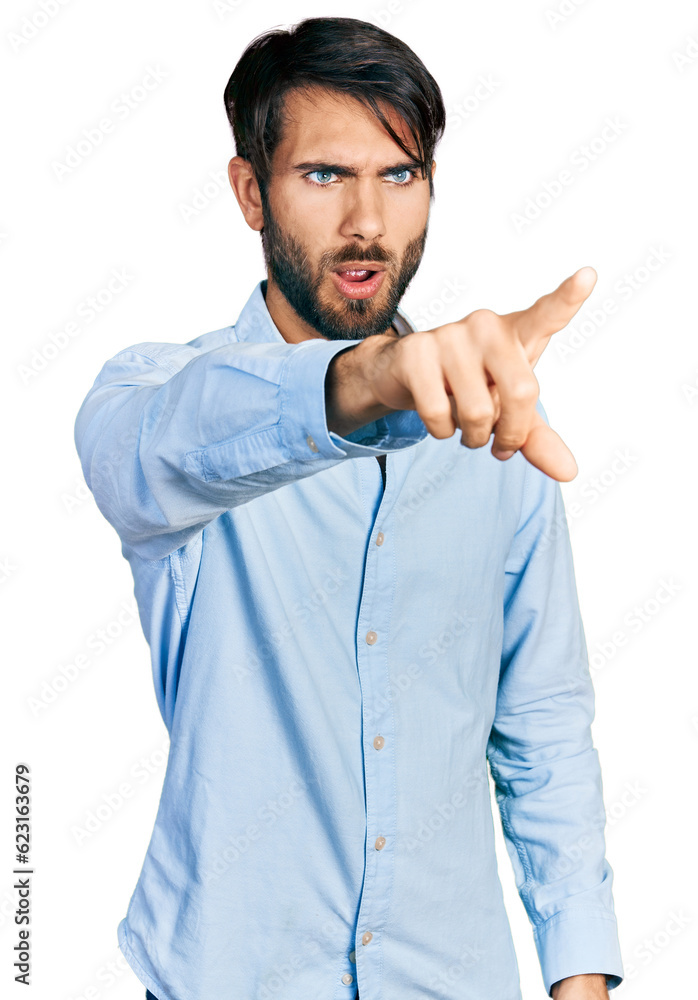 Hispanic man with blue eyes wearing business shirt pointing with finger surprised ahead, open mouth amazed expression, something on the front Hispanic man with blue eyes wearing business shirt pointing with finger surprised ahead, open mouth amazed expression, something on the front