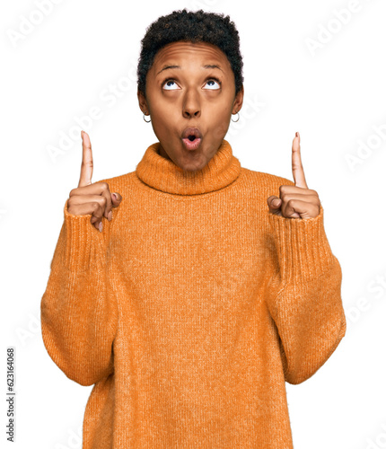 Slika na platnu Young african american woman wearing casual clothes amazed and surprised looking up and pointing with fingers and raised arms