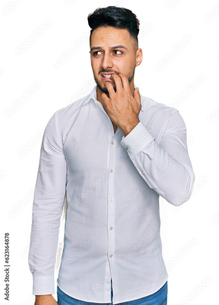 Young arab man wearing casual clothes looking stressed and nervous with hands on mouth biting nails. anxiety problem. Young arab man wearing casual clothes looking stressed and nervous with hands on mouth biting nails. anxiety problem.