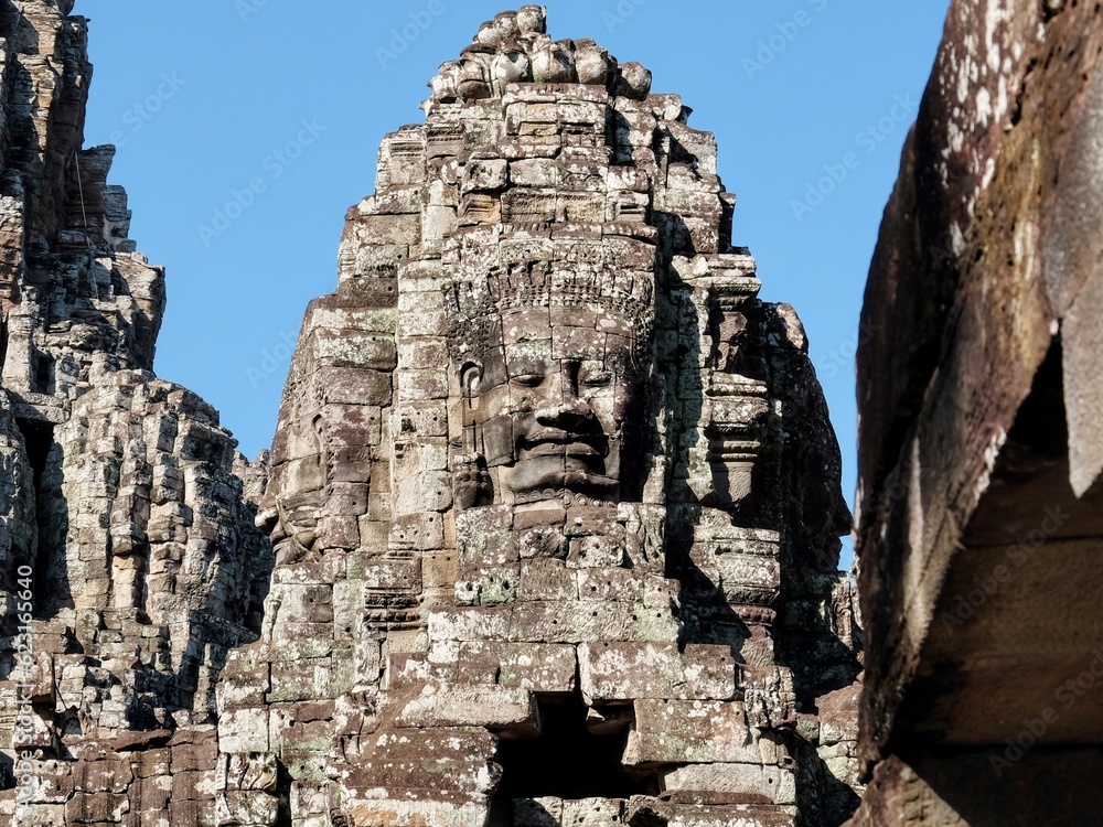 Detailed view of stone human faces adorning the towers of the Bayon Temple, a Khmer site in Cambodia.