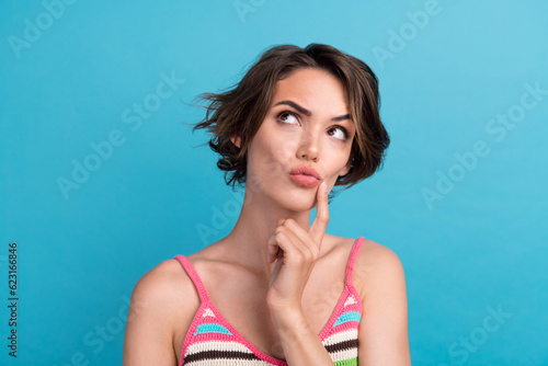 Photo of sweet unsure woman dressed striped tank top finger mouth looking empty space isolated blue color background