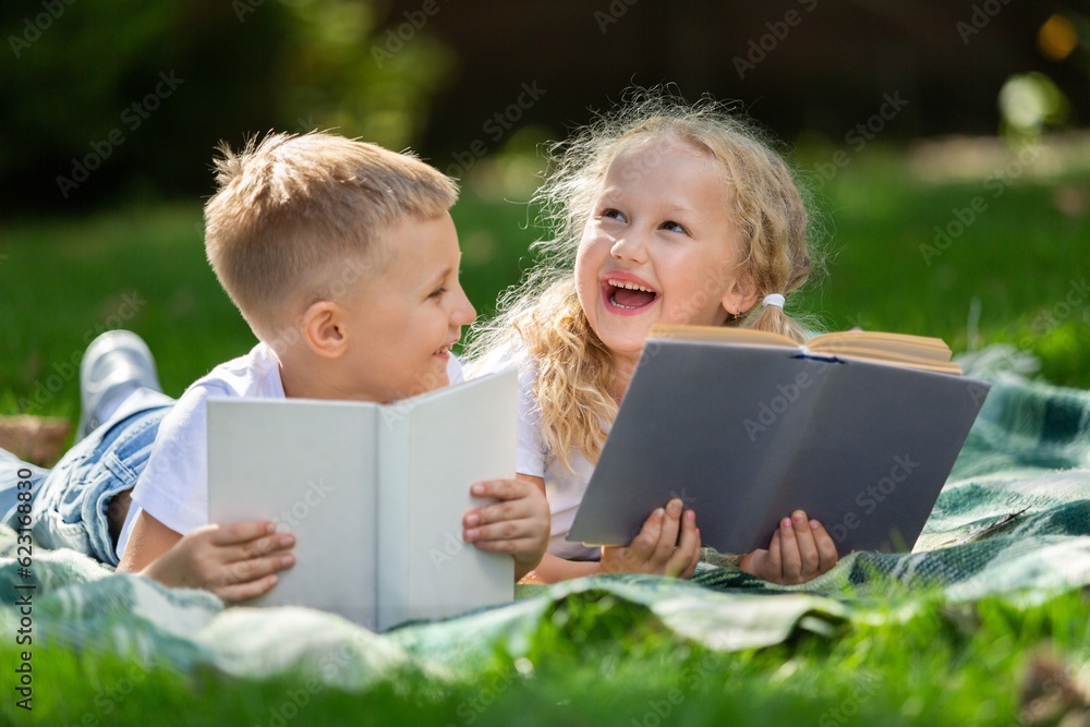 Happy little children's reading books in park Happy little children's reading books in park