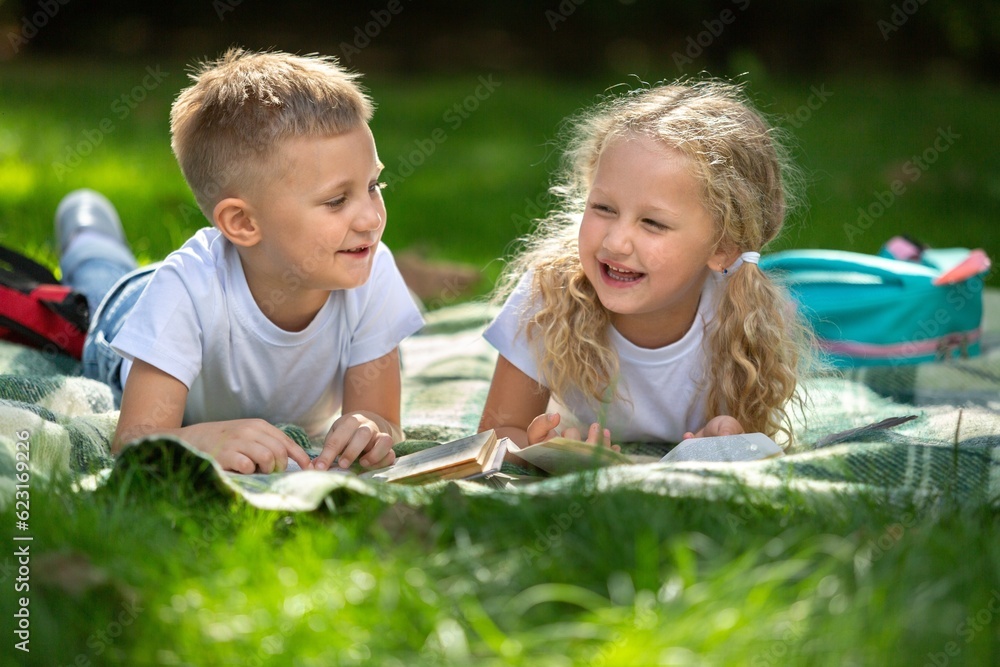 Happy little children's reading books in park Happy little children's reading books in park