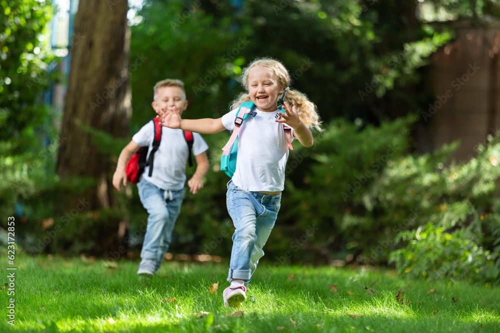 Fototapeta premium Little kids schoolchildren pupils running in park from school.
