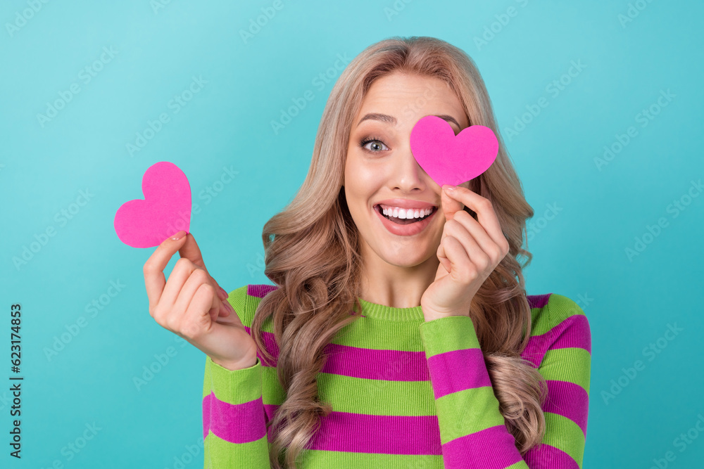 Photo of lovely girlish impressed woman curly hairstyle dressed striped sweatshirt paper heart cover eye isolated on teal color background Photo of lovely girlish impressed woman curly hairstyle dressed striped sweatshirt paper heart cover eye isolated on teal color background
