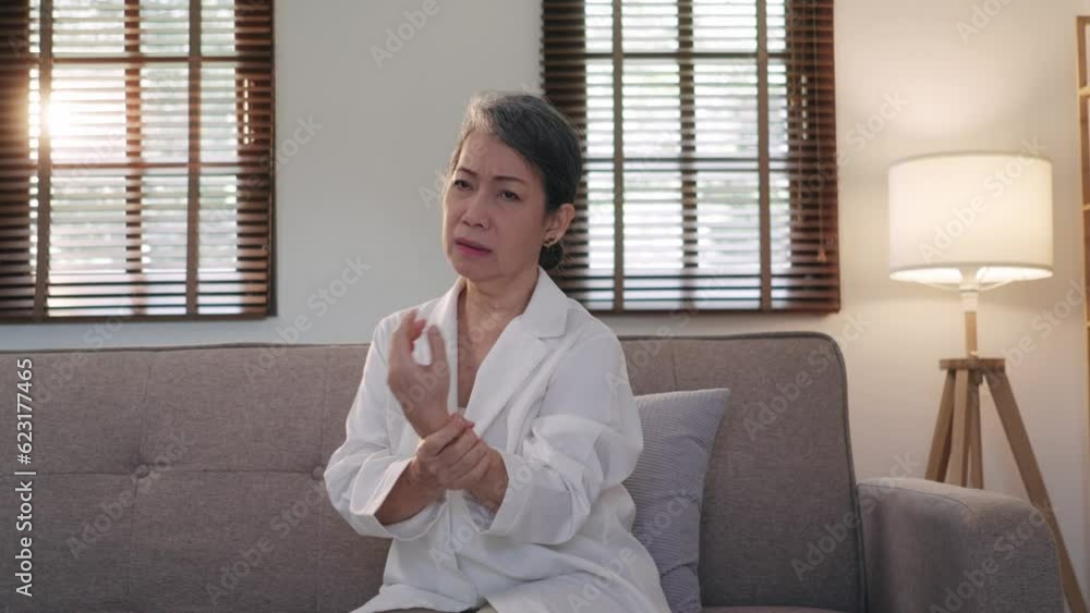 60s aged Asian woman massaging her wrist, feeling pain and swelling in the joints. 60s aged Asian woman massaging her wrist, feeling pain and swelling in the joints.