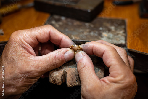 Photography Goldsmith man working in his crafting jewelry workshop repairing and creating a gold ring with a diamond in his work studio