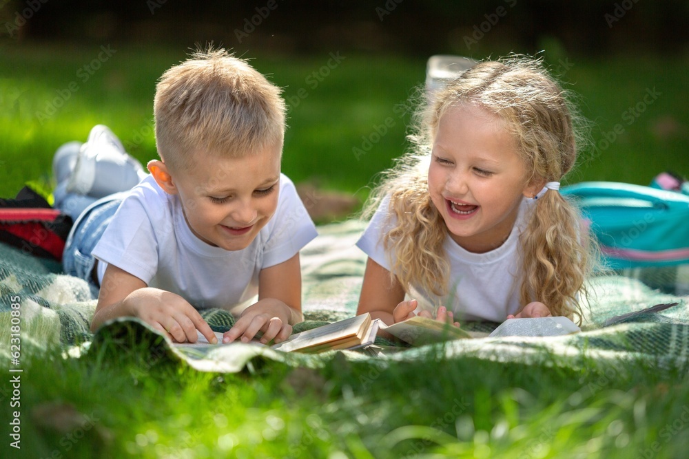 Happy little children's reading books in park Happy little children's reading books in park