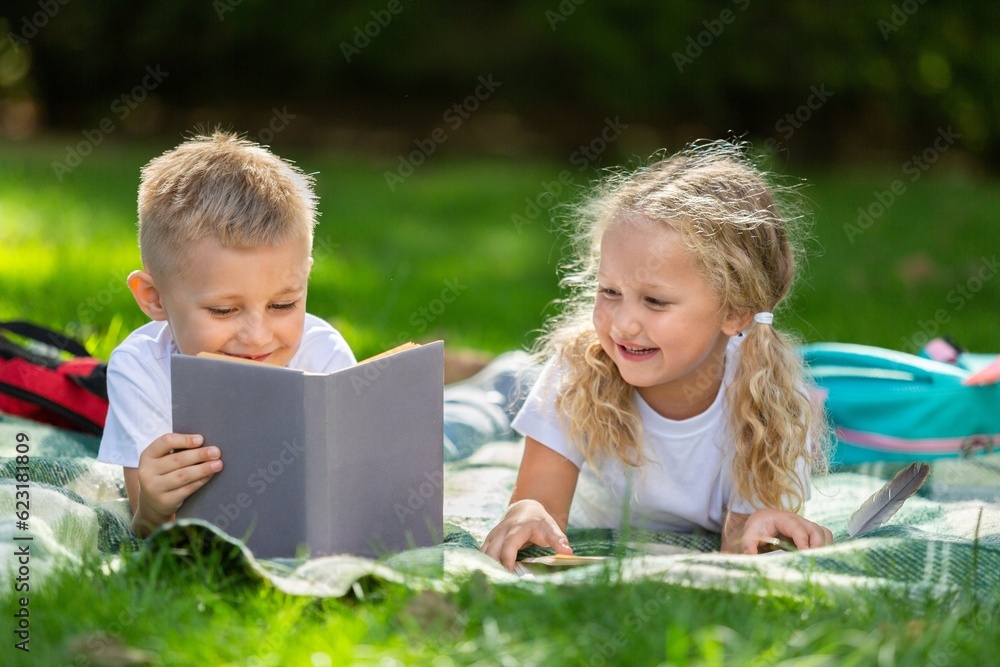 Happy little children's reading books in park Happy little children's reading books in park