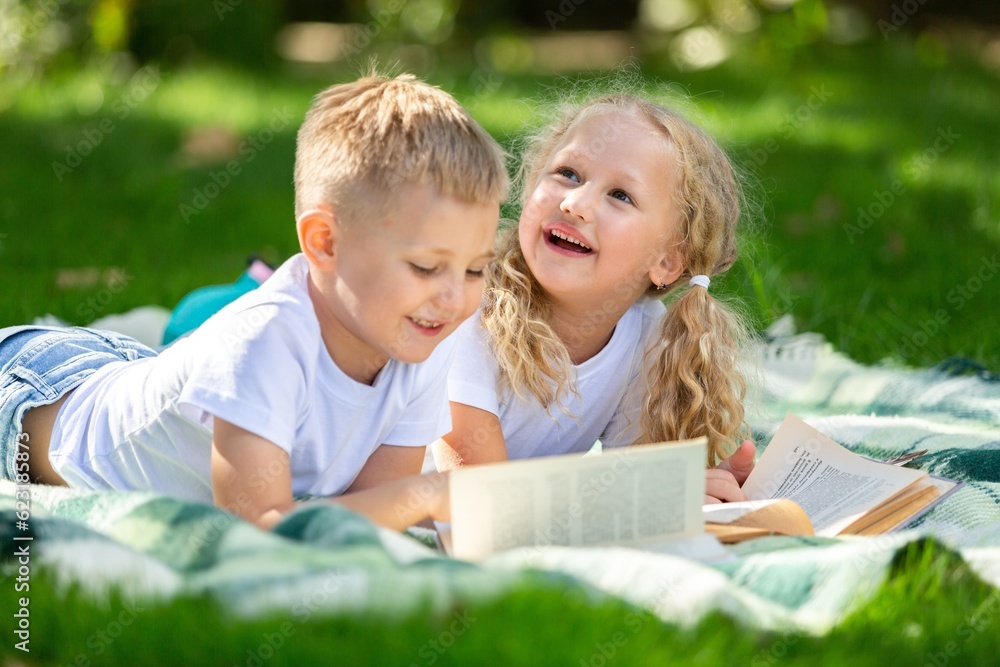 Happy little children's reading books in park Happy little children's reading books in park