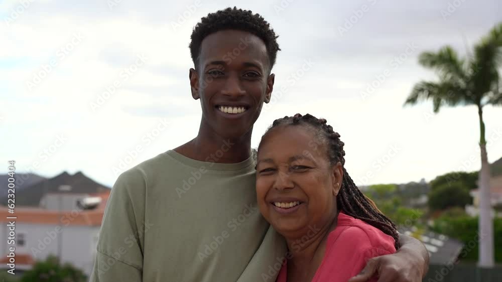 Happy african mother and adult son hugging each other while smiling in front of camera at house rooftop terrace
Happy african mother and adult son hugging each other while smiling in front of camera at house rooftop terrace