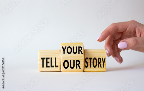 Tell Your or Our story symbol. Businessman hand points at wooden cubes with words Tell Our story and Tell Your story. Beautiful white background. Business concept. Copy space