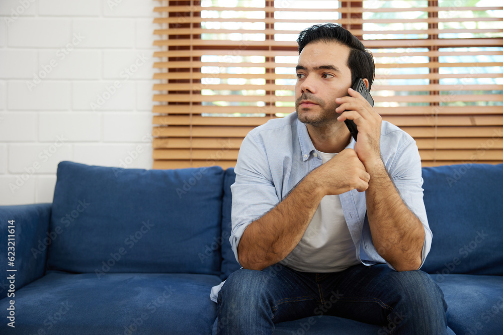 young handsome man sitting on sofa and talking by smartphone at home young handsome man sitting on sofa and talking by smartphone at home