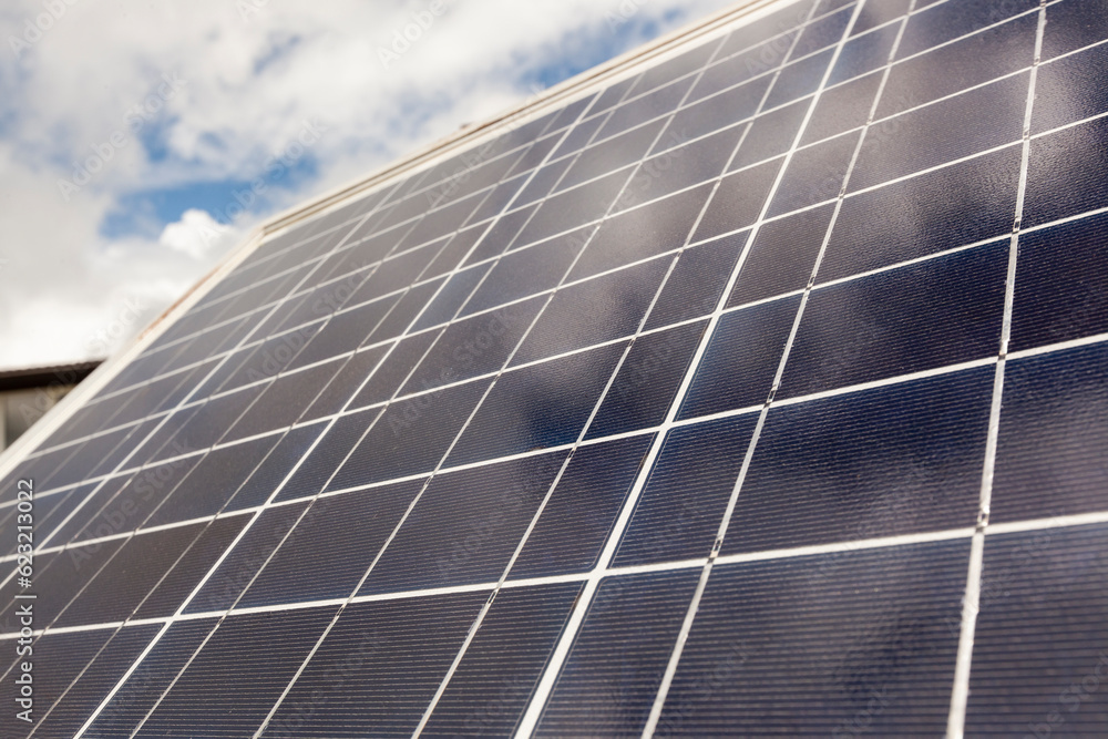 Solar panels on the background of a house with a field and green grass Solar panels on the background of a house with a field and green grass