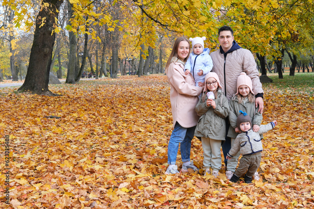 Large family posing in the autumn park. The family consists of mother, father and four children.