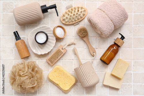 Set of different bath supplies with massage brushes on light tile background