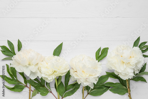 Composition with beautiful peony flowers on light wooden background