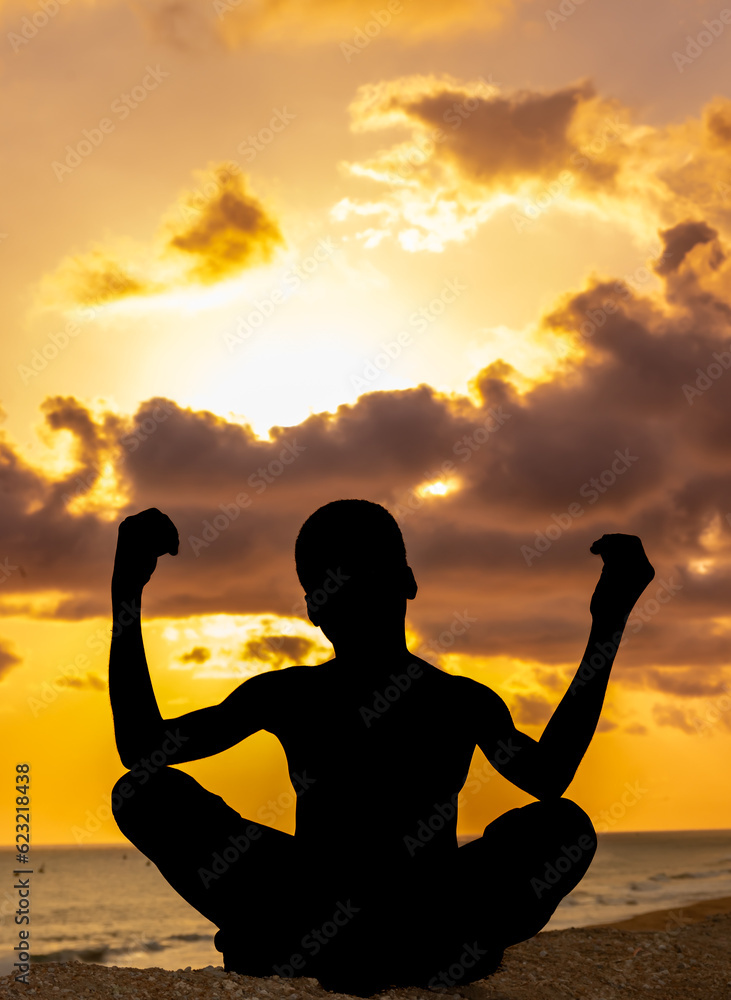 An evocative portrayal of a young boy, his body gracefully stretched in a yoga posture, silhouetted against the captivating solstice sunset near the ocean.