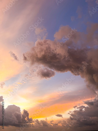 Sunset on the ocean with purple, orange and blue lights colouring the sky. Monsoon clouds surrounding golden setting sun. Far away it's raining at the horizon. Wide shot. Copy space, wallpaper, dream