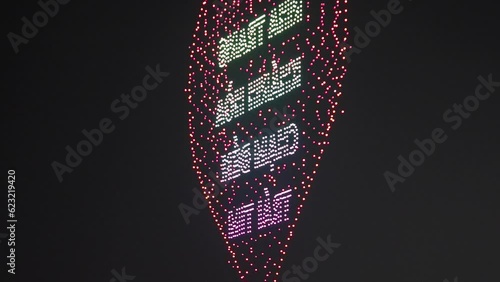 4K footage of glowing flying drones creating a 3D model of a heart in the amusement park. Asian style. Entertainment park concept