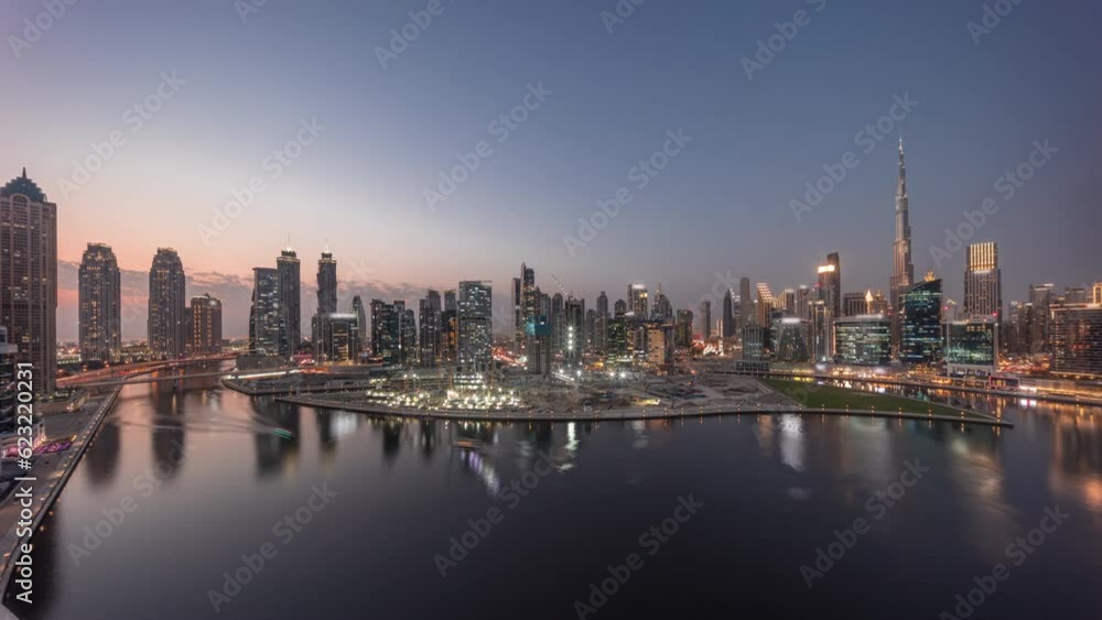 Aerial panorama of Dubai Business Bay and Downtown with the various skyscrapers and towers along waterfront on canal day to night transition timelapse. Construction site with cranes after sunset Aerial panorama of Dubai Business Bay and Downtown with the various skyscrapers and towers along waterfront on canal day to night transition timelapse. Construction site with cranes after sunset