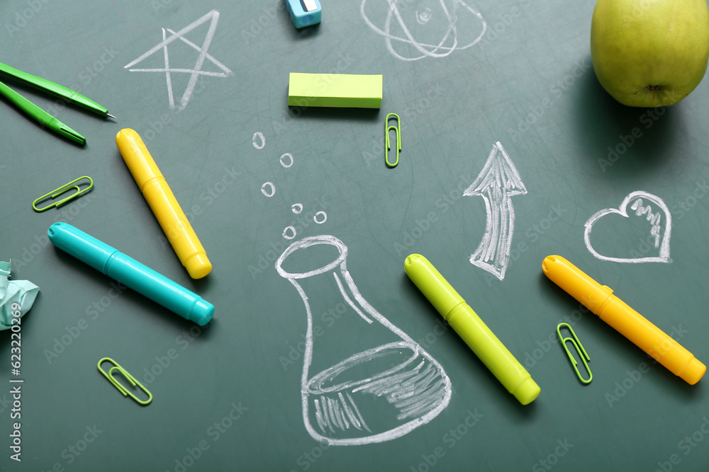Different stationery with drawings on green chalkboard Different stationery with drawings on green chalkboard