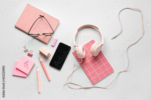 Different stationery with headphones, mobile phone and eyeglasses on grey background