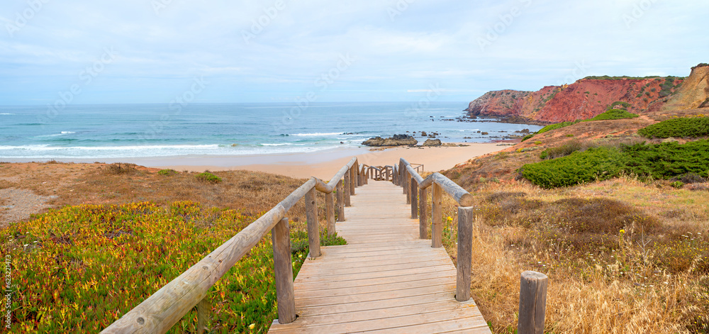 beautiful Amado beach, with boardwalk, red cliffs and mediterranean plants. surfer spot Algarve