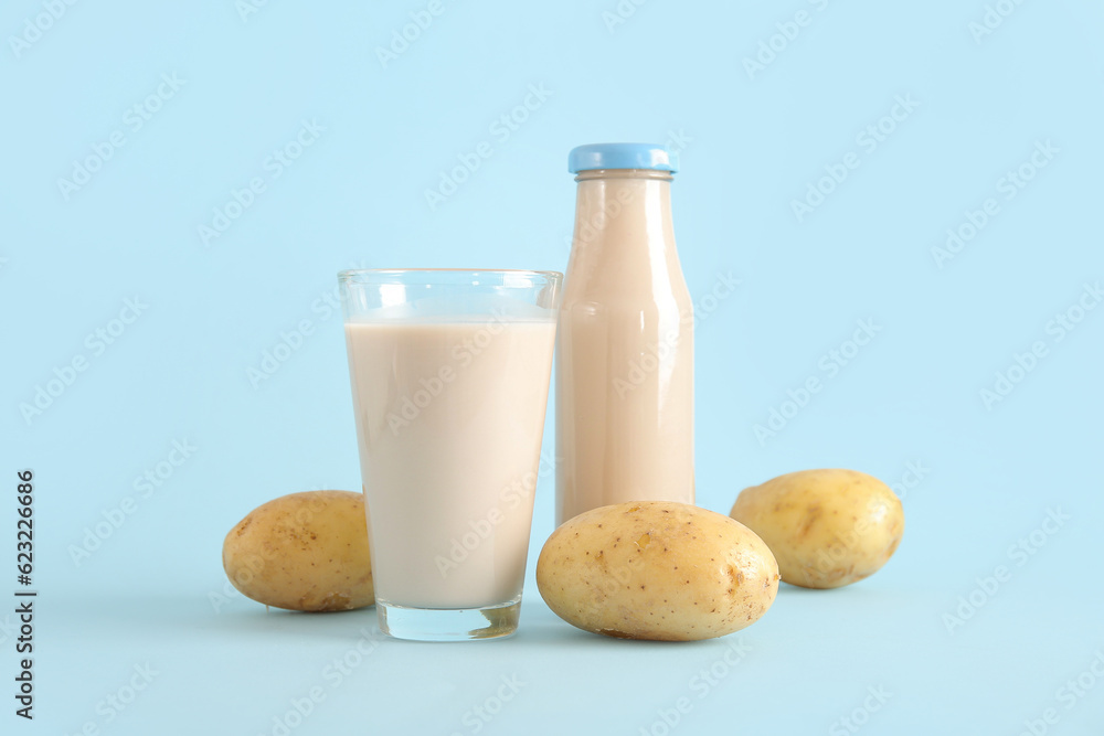 Bottle and glass of tasty potato milk on blue background Bottle and glass of tasty potato milk on blue background