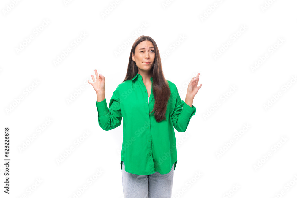 young brown-haired female model with brown eyes in a green shirt doubts on a white background with copy space for text young brown-haired female model with brown eyes in a green shirt doubts on a white background with copy space for text