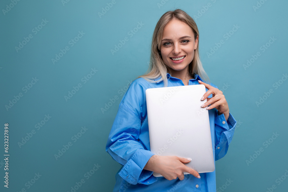 smiling cheerful blond girl student with a laptop computer on a bright blue background smiling cheerful blond girl student with a laptop computer on a bright blue background