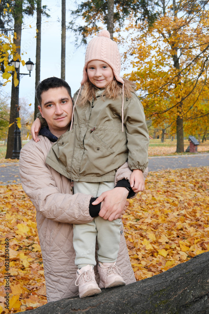 The father is holding his daughter in his arms. Family spending time together in the park The father is holding his daughter in his arms. Family spending time together in the park