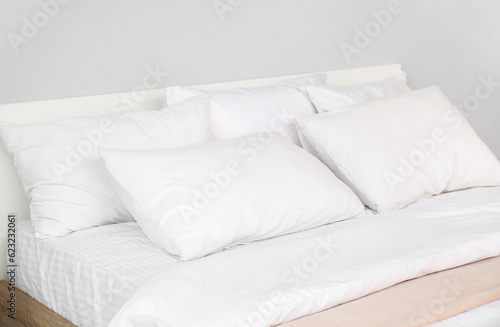 Large double bed with white pillows in interior of light bedroom