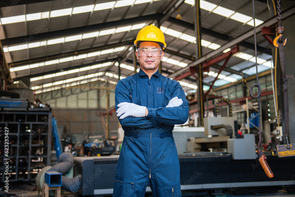 engineer man wearing bodysuit and yellow contruction helmet holding his arms with white gloves with lathe factory background engineer man wearing bodysuit and yellow contruction helmet holding his arms with white gloves with lathe factory background