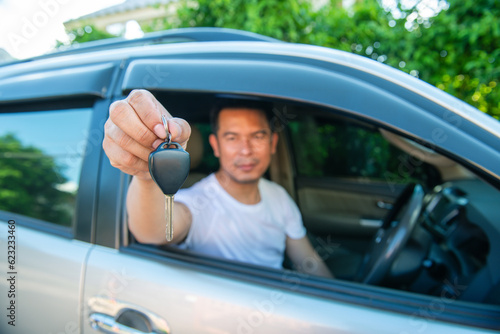 a man wearing a white shirt showing his car key with happy mood