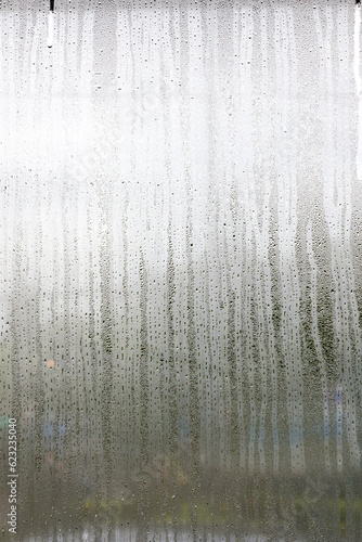 Misted glass  silver rain drops dew drops on transparent glass window. Wet misted glass with drops of water and dew..