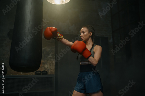 Strong female fighter boxing with punching bag having workout training © Nomad_Soul