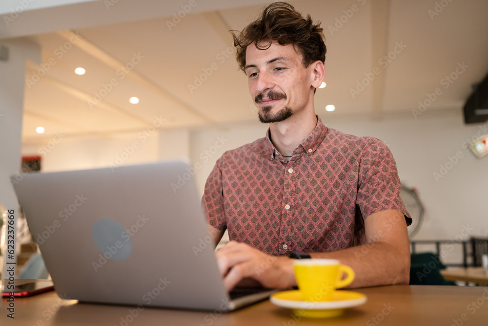 One young adult caucasian man work remote from cafe on laptop computer One young adult caucasian man work remote from cafe on laptop computer