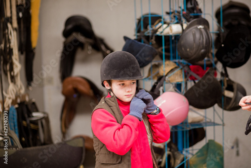 Hispanic boy wear protective Horse riding helmet for safety in equitation sport. Riding school